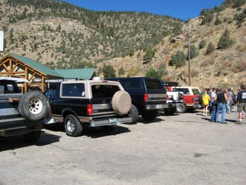 1996 Ford Bronco - A line of SUVs, including a 1996 Ford Bronco, parked outside a Starbucks.