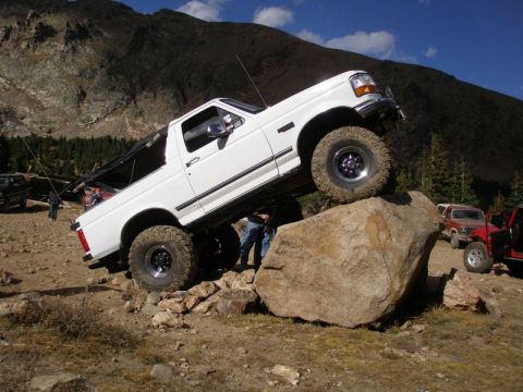 1996 Ford Bronco - A white Ford Bronco navigates a rocky obstacle course in a mountainous terrain.