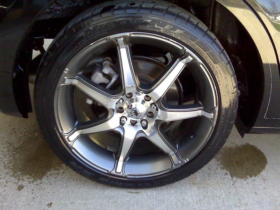 7-spoke gunmetal alloy wheel with low-profile tire on a black car