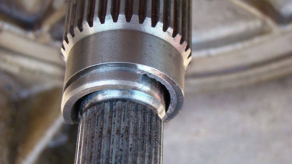 Close-up of splined metal shaft showing chipped/damaged collar edge below the splines