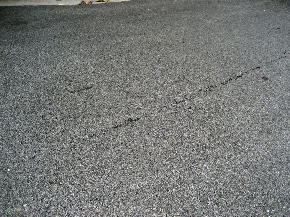 Tire marks on asphalt surface. Some dark spots are visible