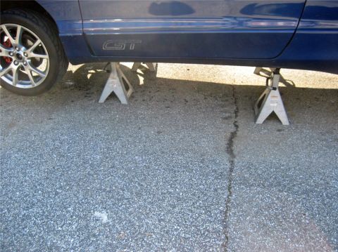 1993 Ford Probe - Side view of a blue car with a GT badge, supported by jack stands.