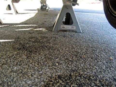1993 Ford Probe - Vehicle is supported by jack stands and a floor jack on a gravel surface.