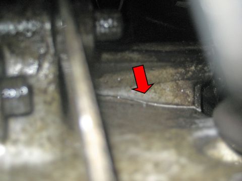1993 Ford Probe - A red arrow highlights a crack on a dirty engine part, indicating a potential mechanical issue.