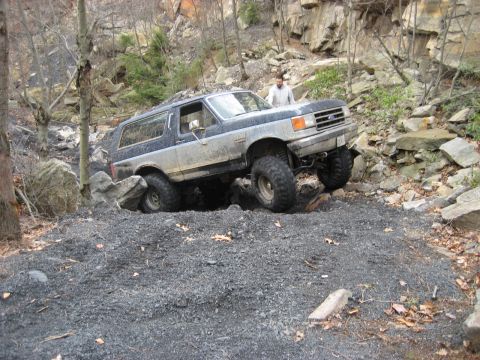 1991 Ford Bronco - A Ford Bronco navigates a challenging off-road course with large rocks and steep inclines.