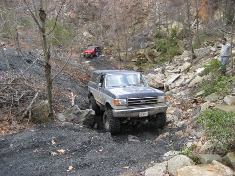 1991 Ford Bronco - A 1991 Ford Bronco tackles a challenging rocky path, with another off-road vehicle in the background.