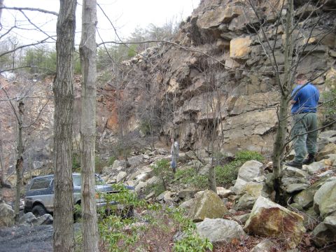 1991 Ford Bronco - A Ford Bronco navigates a rocky, wooded area with a steep cliff in the background.