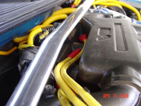 1993 Ford Probe - Close-up view of an engine bay, yellow spark plug wires and a silver strut bar.