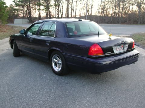 1999 Ford Crown Victoria - Rear view of a dark blue sedan with chrome wheels and a Massachusetts license plate.