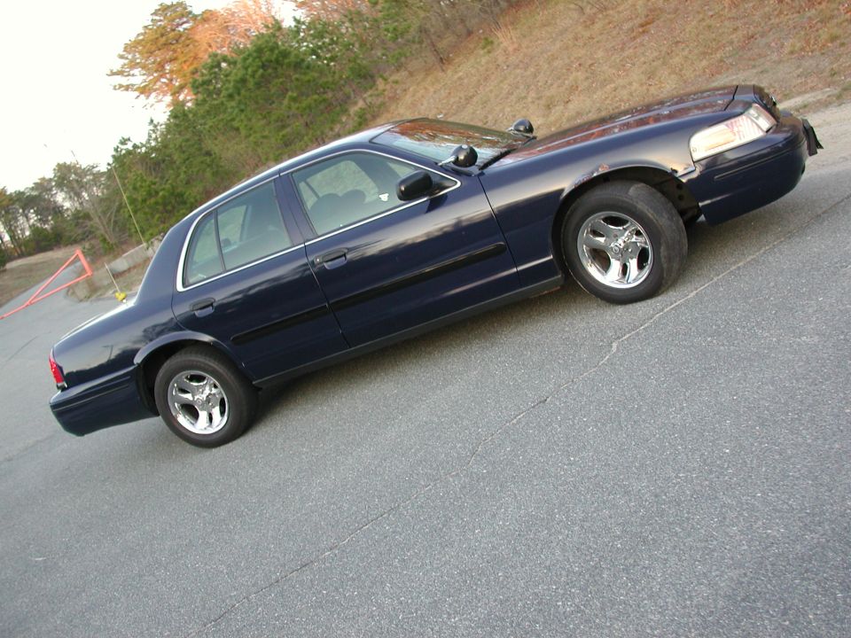 Dark blue sedan parked on asphalt. It has chrome wheels and black trim