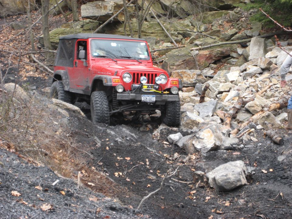Red Jeep Wrangler Rubicon navigating a rocky trail