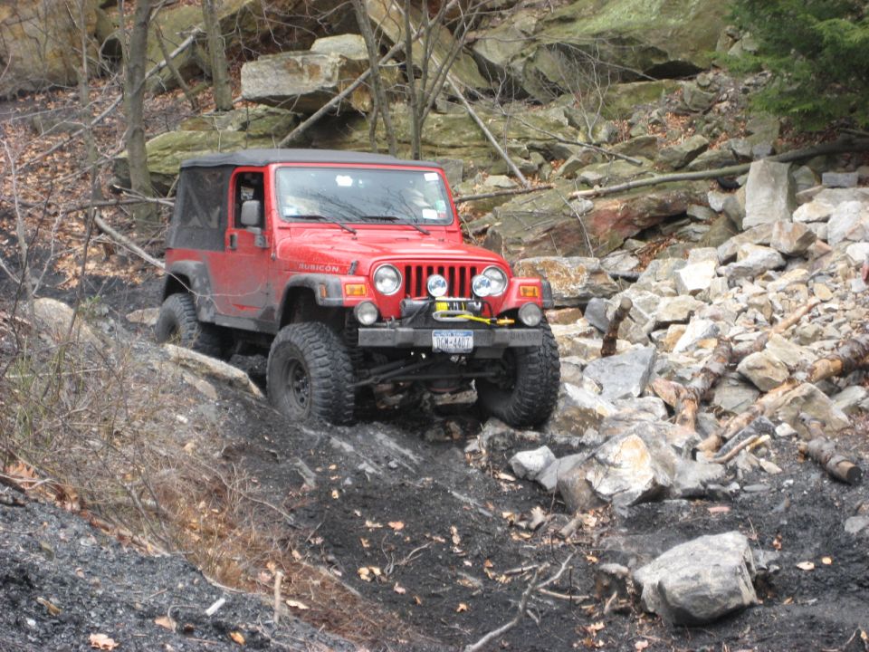 Red Jeep Wrangler Rubicon with winch on rocky trail. License plate reads "KCM-0401"