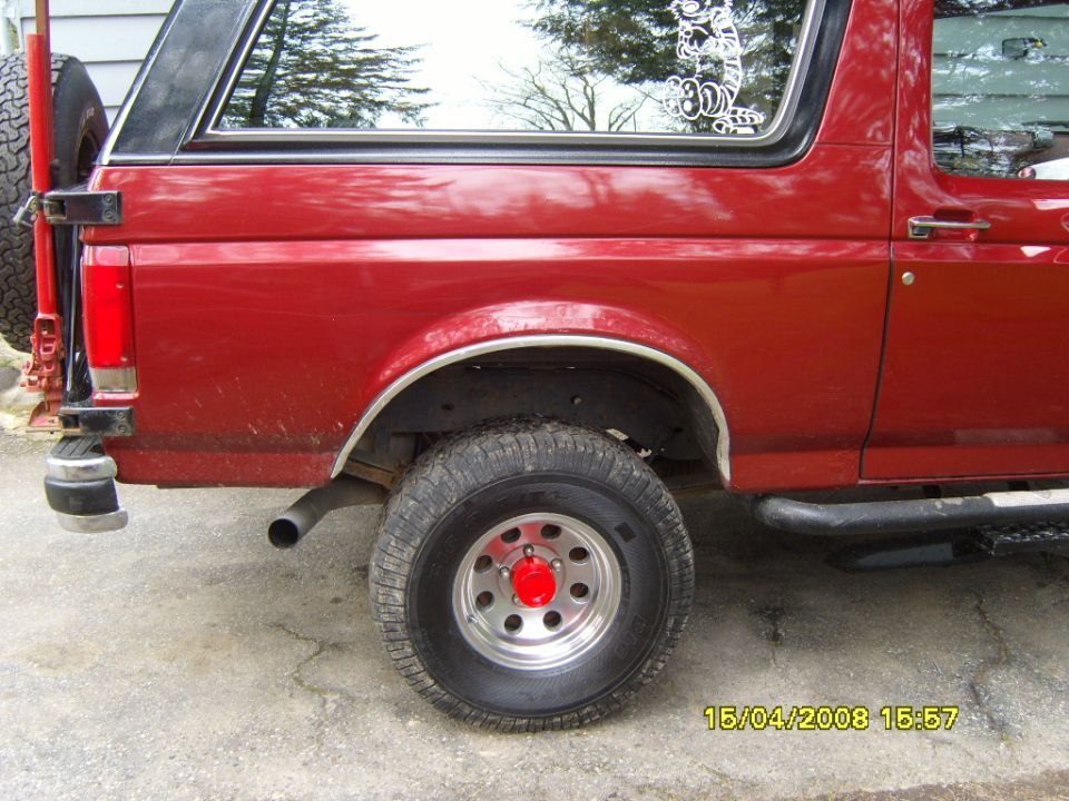 Red SUV rear quarter panel with spare tire mounted on the back and a sticker on the window