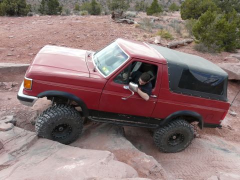 1990 Ford Bronco - This red SUV is shown off-roading on a rocky trail.
