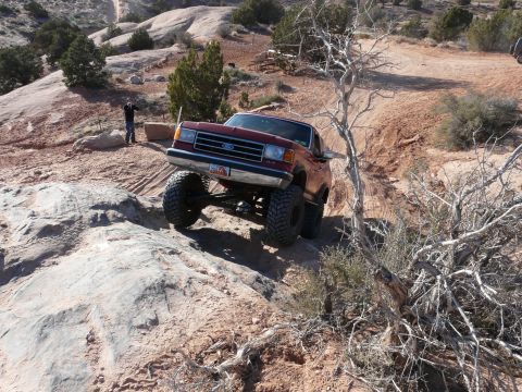 1990 Ford Bronco - A lifted Ford Bronco navigates a rocky trail, its off-road capabilities.