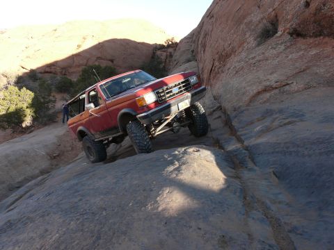 1990 Ford Bronco - A red 1987 Ford Bronco navigates a challenging rocky terrain during an off-road event.