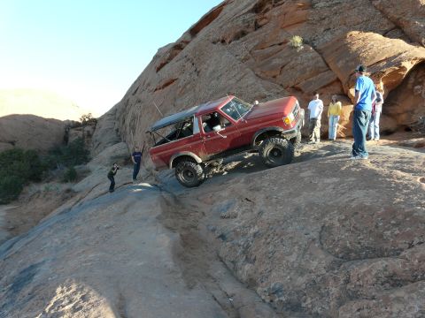 1990 Ford Bronco - Red 1990 Ford Bronco navigates challenging off-road terrain during an event.