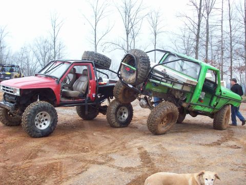 1978 Ford Bronco - Two heavily modified off-road trucks are positioned side-by-side in an outdoor setting.