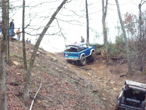 1978 Ford Bronco - A blue 1978 Ford Bronco navigates a steep, wooded incline with another vehicle visible below.