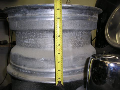 1987 Ford Bronco - A close-up view of a wheel rim with a yellow tape measure indicating its size.