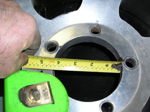 1987 Ford Bronco - A hand uses a measuring tape to measure a wheel rim, indicating a part rather than a complete vehicle.
