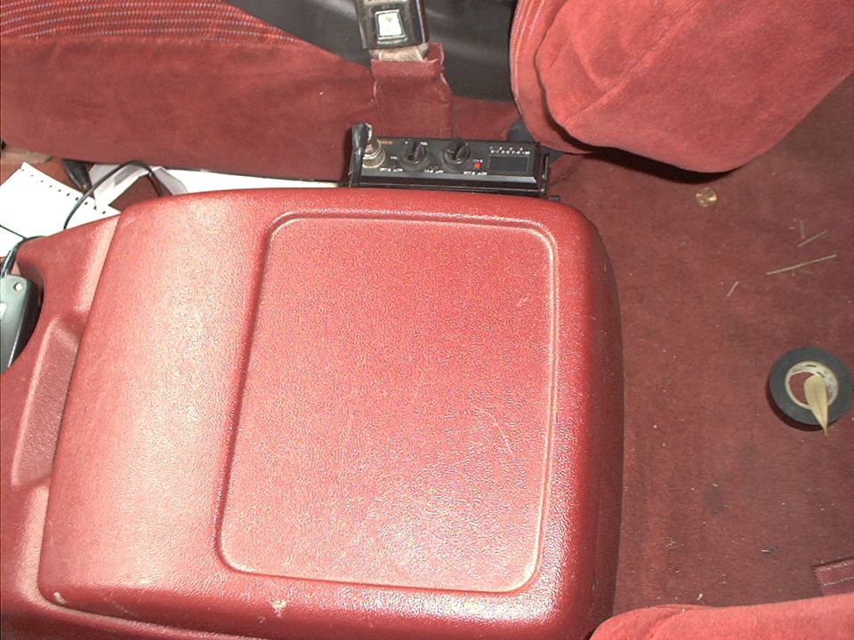 Red center console and CB radio between red cloth seats inside a Ford Bronco interior