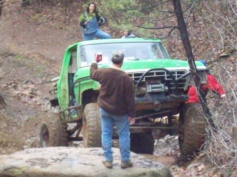 1978 Ford Bronco - A heavily modified 1978 Ford Bronco navigates a muddy off-road trail with passengers.