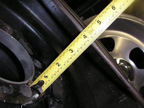 1987 Ford Bronco - A yellow tape measure is used to measure a component of a vehicle, with a wheel visible in the background.