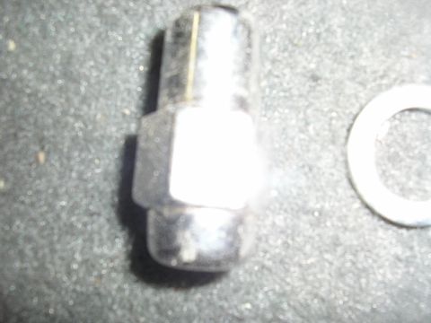 1987 Ford Bronco - A single lug nut and a washer are shown on a textured surface.