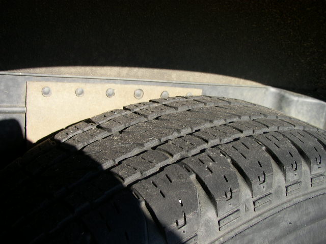 Tire tread and riveted metal panel in wheel well