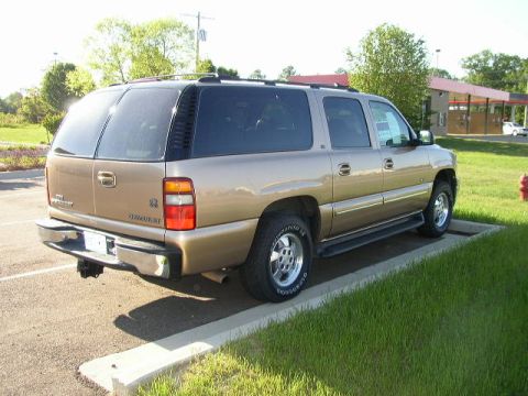 1995 Ford Bronco - This Chevrolet Suburban is parked in a grassy area next to a paved lot.