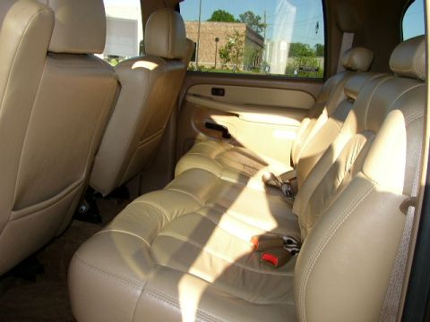 1995 Ford Bronco - The interior of a vehicle shows tan leather seats and door panels, with light filtering through the windows.