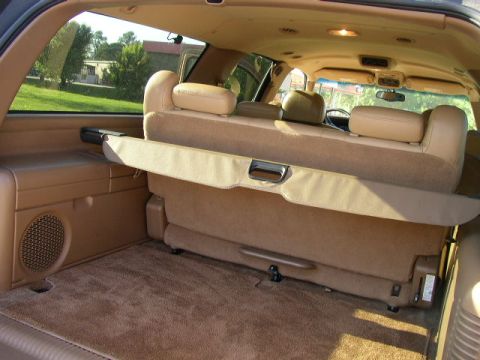 1995 Ford Bronco - The interior cargo area of a tan SUV shows folded rear seats and a retractable cargo cover.