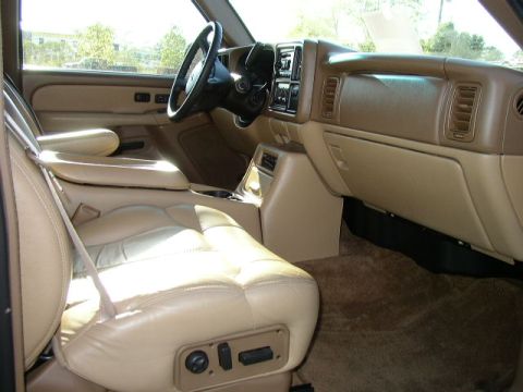1995 Ford Bronco - The interior of a truck shows tan leather seats and dashboard with power seat controls.