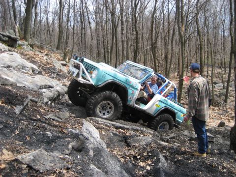 1991 Ford Bronco - A light blue 1978 Ford Bronco navigates a steep, rocky incline during an off-road event.
