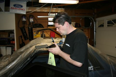 1992 Ford Crown Victoria - Man works on the interior of a car covered in plastic sheeting in a garage.