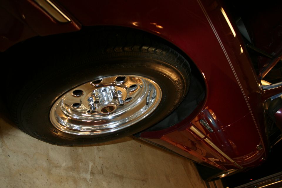 Close-up of a chrome wheel and dark red fender on a car