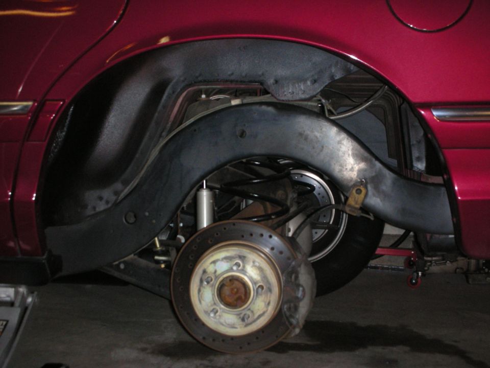 Red 1992 Ford Crown Victoria rear wheel well with drilled rotors and aftermarket suspension components visible