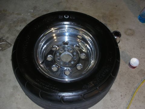 1992 Ford Crown Victoria - A close-up view of a tire mounted on a shiny chrome wheel, resting on a concrete floor.