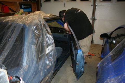1990 Ford Mustang - Mechanic works on the interior of a 1990 Ford Mustang, which is covered in protective plastic sheeting.