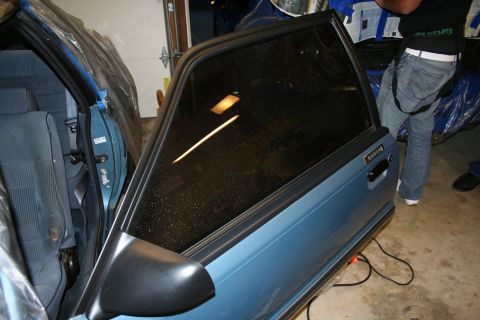 1990 Ford Mustang - The side view of a blue 1990 Ford Mustang shows its open door and interior, with a person standing nearby.