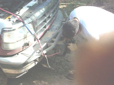 1994 Ford Bronco - Someone is working on the front of a 1992 Ford Bronco, possibly jump-starting it.