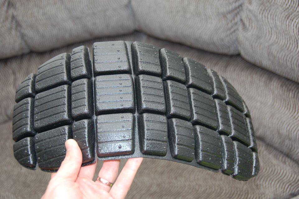 Black motorcycle tire tread held by a hand. Supermotors.net logo visible