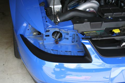 1998 Ford Crown Victoria - front corner of a blue car sits with bumper cover and headlight removed, exposing the engine bay.