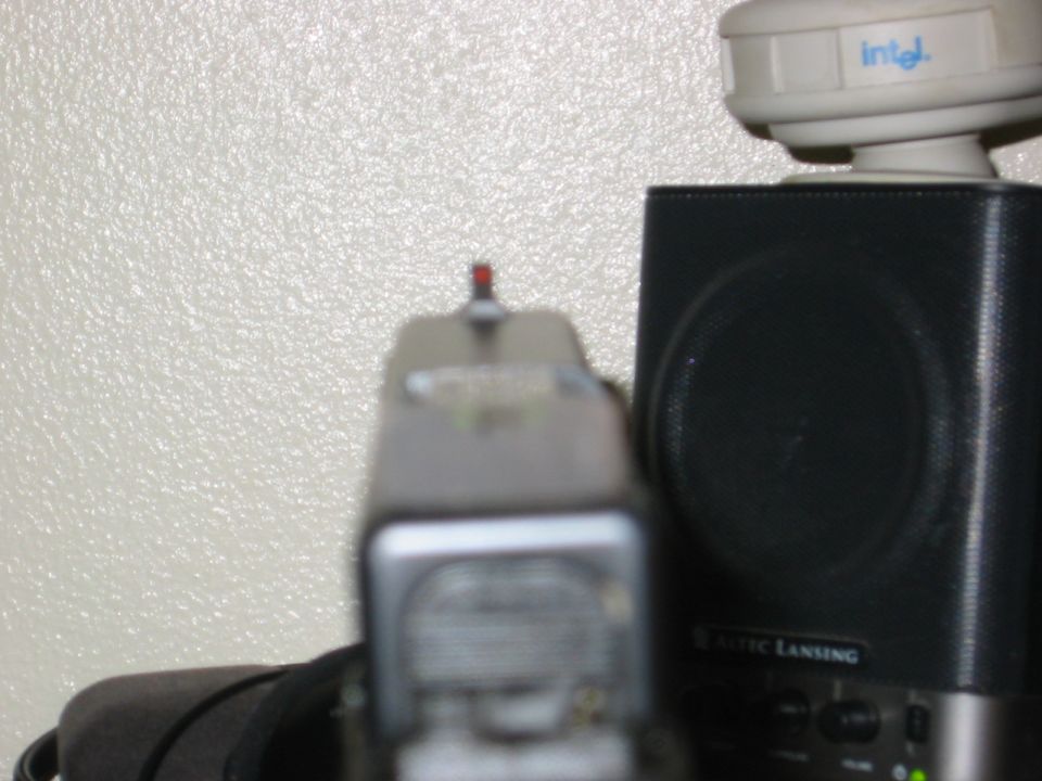 Pistol sights with a red front sight dot, next to a speaker and an Intel device