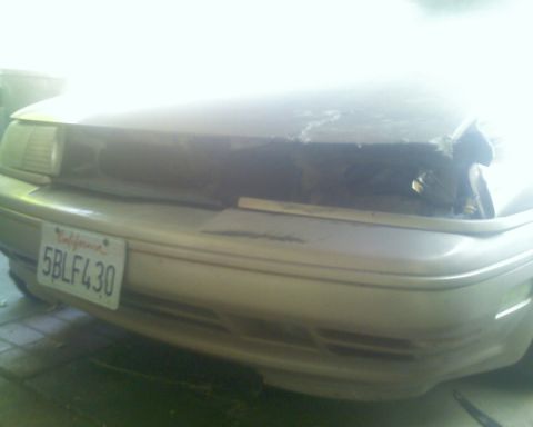 1991 Ford Taurus - Front view of a damaged 1991 Ford Taurus, showing the grille and headlight area.