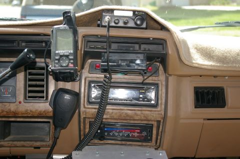 1986 Ford Bronco - The dashboard of the vehicle features several electronic accessories, including a GPS unit and a CB radio.