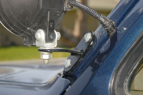 1986 Ford Bronco - Detail of an auxiliary light bracket attached to the fender of a blue vehicle.