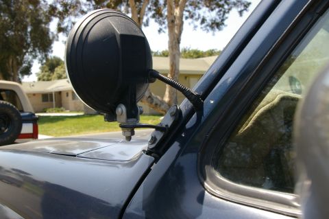 1986 Ford Bronco - Close-up of an off-road light attached to the fender of a vehicle, with a second vehicle in the background.