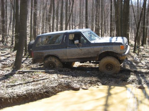 1991 Ford Bronco - A Ford Bronco attempts to drive through a muddy, wooded area, getting stuck in the mire.